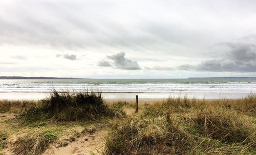 Scenic view of calm sea against cloudy sky