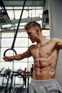 Shirtless man exercising in gym