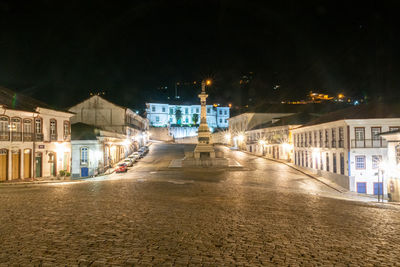 Illuminated street amidst buildings in city at night