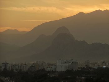 Silhouette buildings in city against sky at sunset