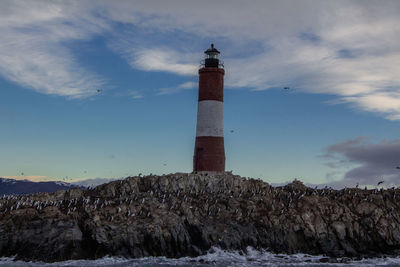 Lighthouse by sea against sky