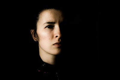 Portrait of young woman against black background