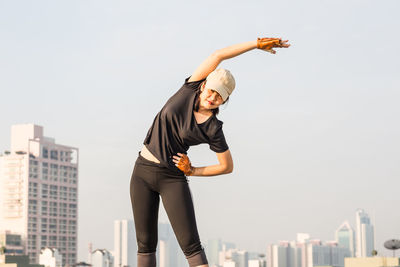 Woman exercising against sky