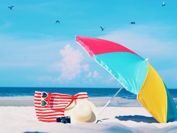 Colorful beach umbrella on sand against sky during summer