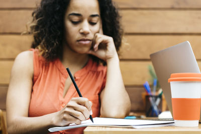 Close-up of woman using mobile phone while sitting on table