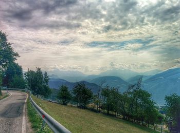 Road passing through landscape against cloudy sky