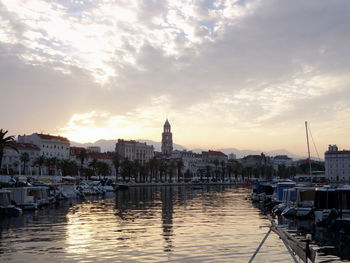 View of buildings at waterfront against cloudy sky