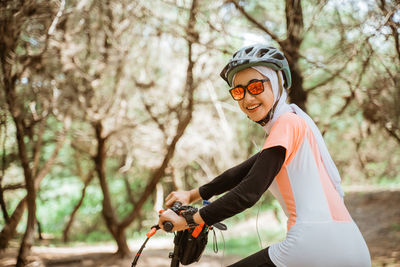 Portrait of young woman on bicycle at park