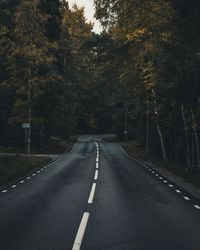 Empty road amidst trees in forest