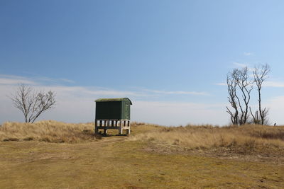 Lifeguard hut on field against sky
