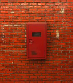 Fire extinguisher box on red brick wall