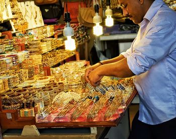 Midsection of man working at illuminated shop