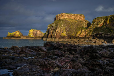 Rock formations by sea against sky