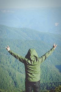 Rear view of men with arms raised standing on mountain