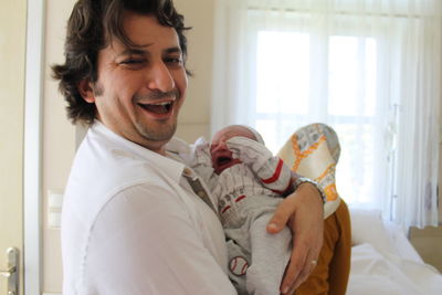 Happy young man holding camera at home