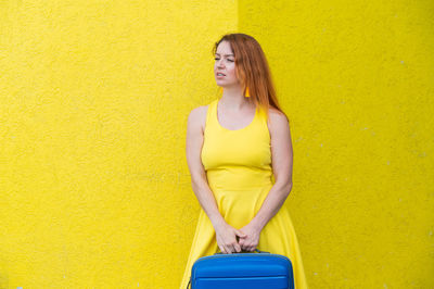 Full length of woman standing against yellow wall