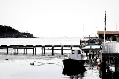 Boats moored at harbor against clear sky