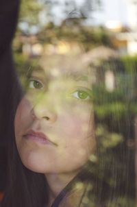 Close-up portrait of serious girl against reflected glass window