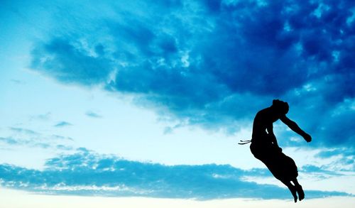 Low angle view of woman jumping against clear sky