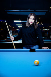 Portrait of young woman playing pool