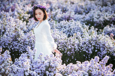 Portrait of beautiful woman standing by flowering plants