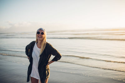 Portrait of smiling young woman standing at beach