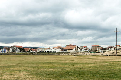 Houses on field against cloudy sky