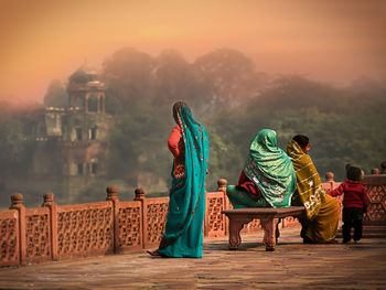 Rear view of people looking at temple against sky