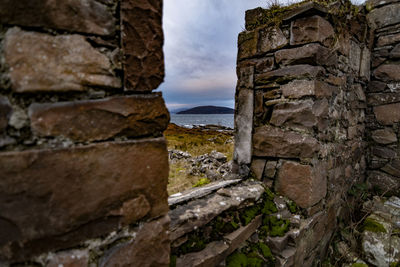 Stone wall by sea against sky