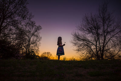 Little girl holding flower silohette long hair summer evening sunset
