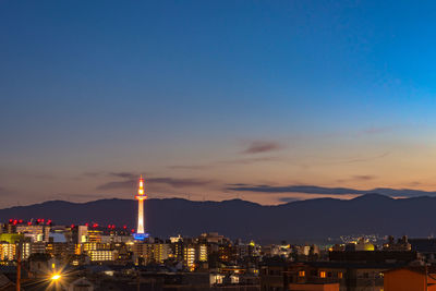 Illuminated buildings in city against sky at sunset