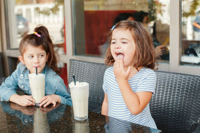 Siblings having milk shake at table in restaurant