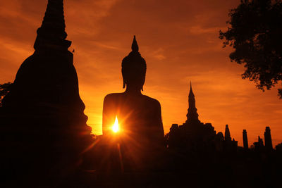 Silhouette statue against sky during sunset