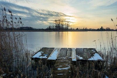 A fishing platform in the reeds and sunset over a calm lake, winter landscape