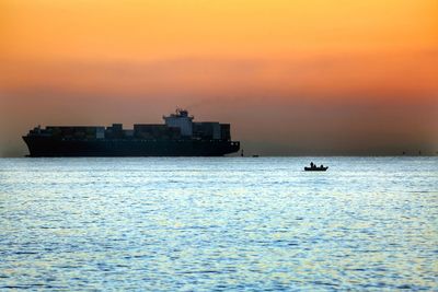 Silhouette boat sailing in sea against sky during sunset