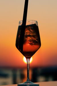 Close-up of wineglass against orange sky