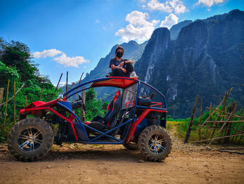 Woman wearing pollution mas sitting on vehicle against mountain