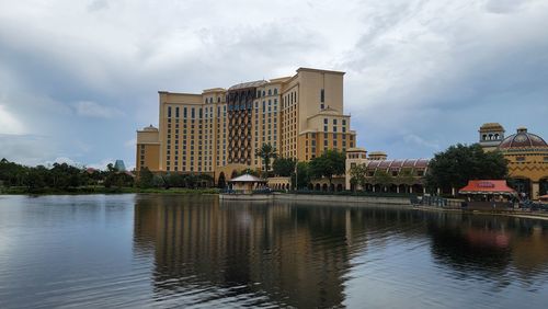 Buildings by river against sky in city