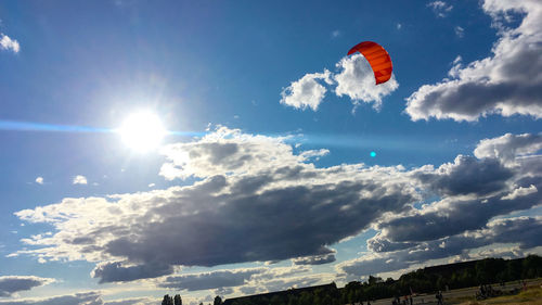 Low angle view of people paragliding against sky