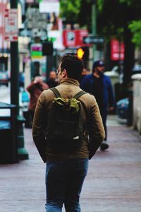 Rear view of man walking on road in city