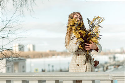 A woman with a bouquet of acacia flowers. the concept of the spring - march 8, easter, women's day