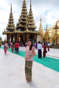 Full length portrait of young woman standing outside temple