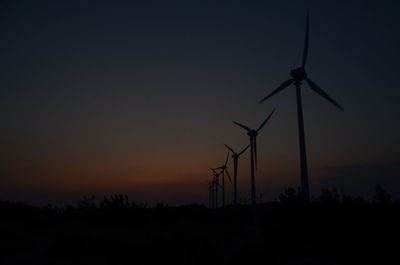 Silhouette wind turbines against sky during sunset