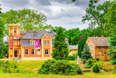 House and trees on field against sky