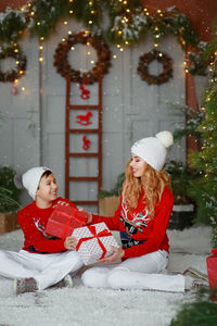 Portrait of smiling woman sitting on christmas tree