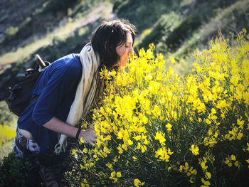 Rear view of person standing on yellow flowering field