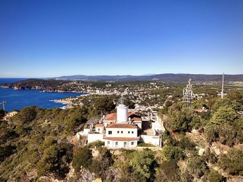 Buildings by sea against clear blue sky