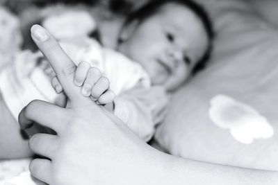 Baby girl holding finger of mother