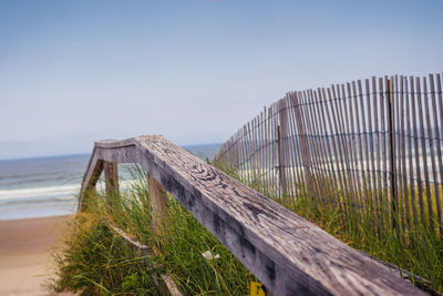 Wooden fence on beach against clear sky