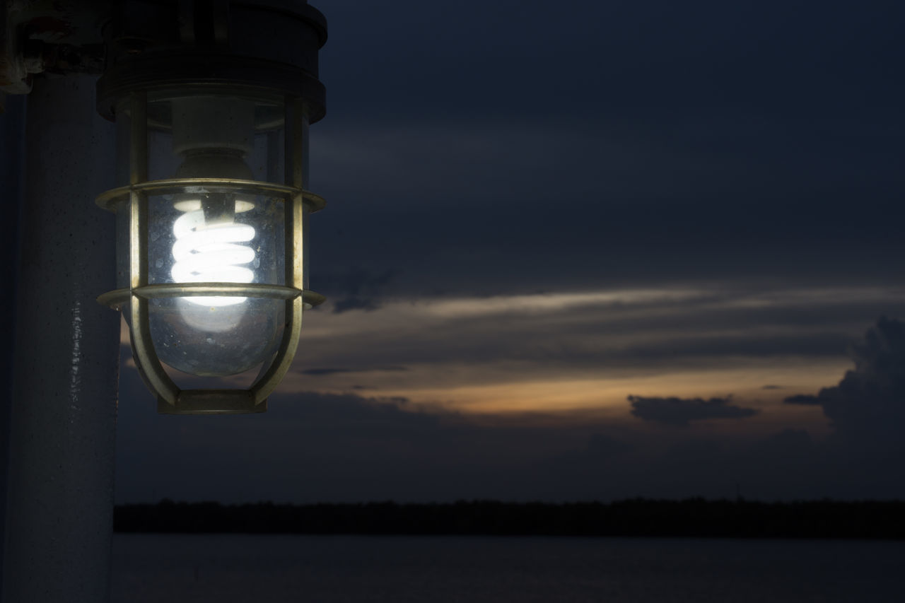 CLOSE-UP OF ILLUMINATED STREET LIGHT AGAINST SKY